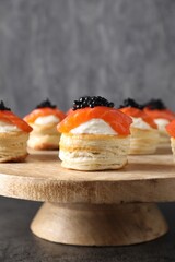 Delicious puff pastry with cream cheese, salmon and black caviar on grey table