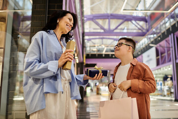 A mother and her son with Down syndrome smile and exchange gifts while walking through a shopping mall.