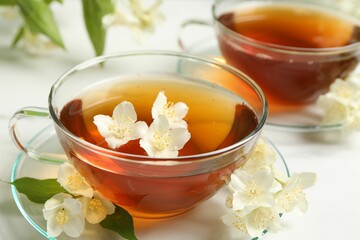 Hot jasmine tea in cup and flowers on white marble table