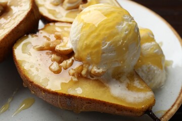 Delicious baked pears with nuts, ice cream and honey on plate, closeup