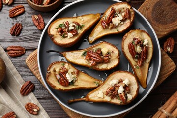 Delicious baked pears with nuts, blue cheese and honey on wooden table, flat lay