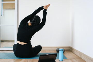 Back view of woman practicing yoga and meditation in yoga studio