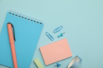 Flat lay composition with notebook and different stationery on light blue background, space for text