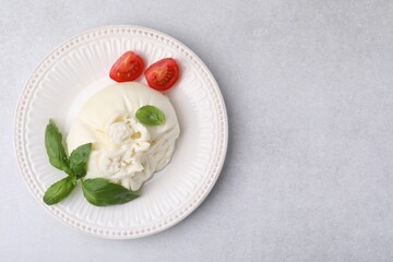 Delicious burrata cheese, tomatoes and basil on light table, top view. Space for text