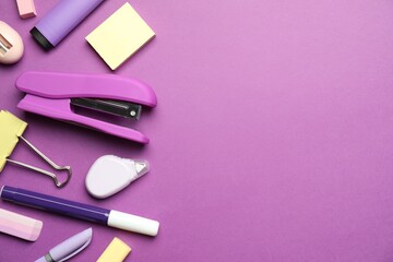 Flat lay composition with stapler and different stationery on violet background, space for text