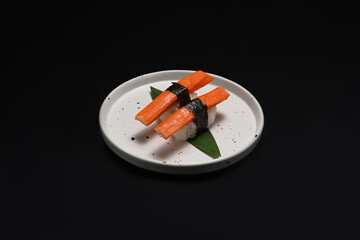 Crab stick Nigiri Sushi in white ceramic plate isolate on black background. Japanese food concept