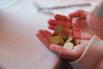 Person holding a handful of gold coins on a dining table