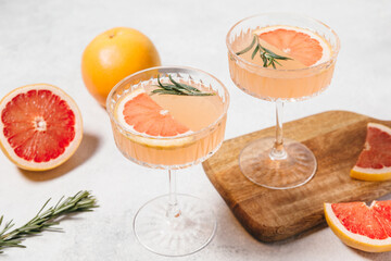 Elegant grapefruit and rosemary cocktails served in crystal glasses with fresh grapefruit slices,...