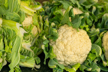 head of cauliflower is surrounded by green leaves