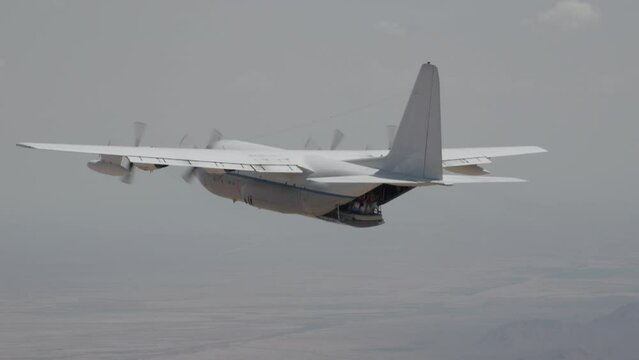 Cinematic slow motion of skydivers falling out of C-130 airplane with inflatable toys