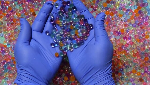 Hands smoothly pour over a bunch of multicolored small balls. Hands are immersed in colorful shiny balls. Asmr. part2.14