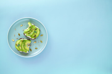 Healthy avocado toast on a blue plate for breakfast or lunch with rye bread, sliced avocado,...