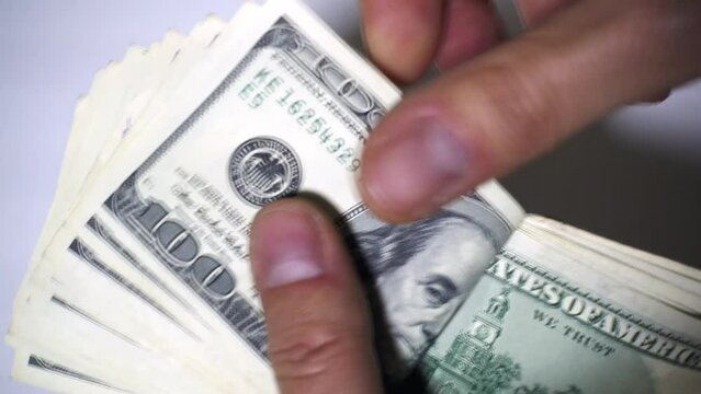 A rich man counts his monthly salary of $ 2,000 us dollars on a white background. Concept of earning, salary, salary, pay the mortgage, monthly expenses, count money, count dollars, earn money