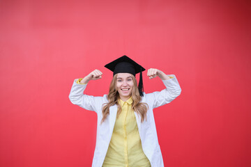 Young blond female in medical uniform and graduation cap looking at the camera and smiling. Standing outside, happy to finish studying in healthcare or veterinary. High quality photo