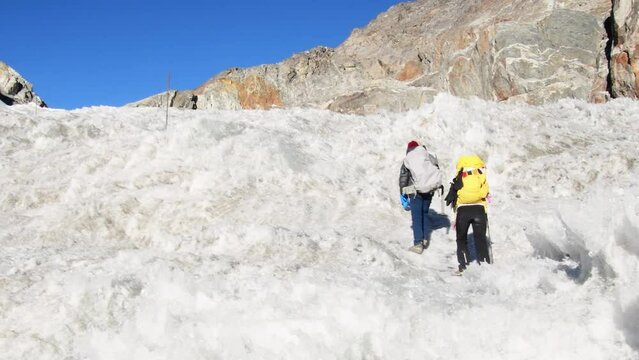 Two trekkers trekking in Himalayas mountains through Chola glacier pass to Gokyo Ri. Nepalese male guide leading tourist client in Sagarmatha national park official trek.