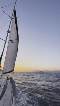 Boat sailing towards the sunset in Agean Sea with islands on the horizon