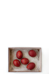 Fresh red eggs and some straw in a wooden crate on a white background. Chicken eggs. Easter concept .Top view