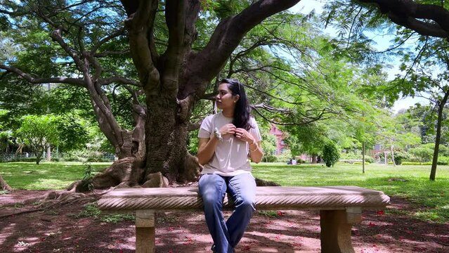 Young Indian woman relaxing and enjoying in cubbon park in a white shirt and jeans in Bangalore, india