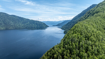 summer panoramic landscape of mountains and forest and waterfall against the sky in the area of ​​Lake Teletskoye in Altai