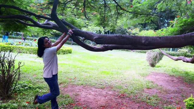 Young Indian woman relaxing and enjoying in cubbon park in a white shirt and jeans in Bangalore, india