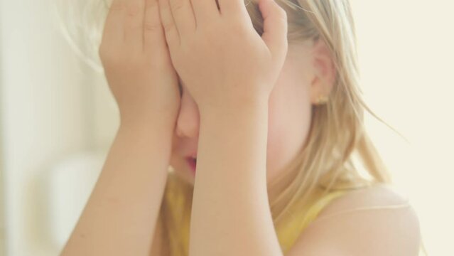 angry blonde girl in soft blurred video covers eyes with hands during tantrum, Toddler tantrum in full swing, Little miss grumpy, Toddler emotions