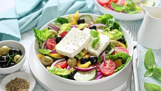 Greek salad. Horiatiki salad. Vegetable salad with feta cheese, tomato, olives, cucumber, bell pepper, lettuce, red onion and olive oil. Mediterranean cuisine. Healthy food. Stock video 4k