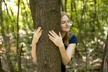 Happy beautiful woman love nature hugging a pine tree. Caring for the environment. The ecology concept of saving the world and love nature by human. Earth Day.