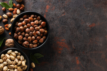 Different types of nuts in black bowls on a dark background
