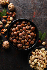 Different types of nuts in black bowls on a dark background