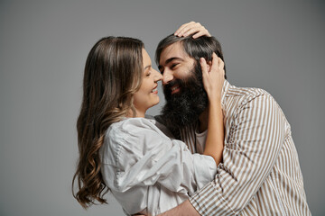 A loving couple in sophisticated attire embrace in a studio setting.