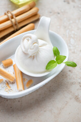 Burrata cheese with grissini or italian bread sticks, vertical shot on a beige granite background, middle close-up