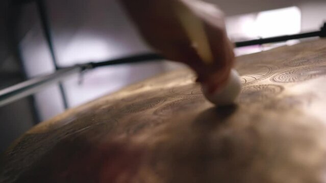 Woman makes the sound of a gong with small soft mallet. Gong and little gong hammer