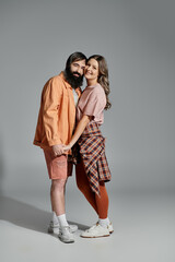 A couple in sophisticated clothing, embracing each other and smiling at the camera.