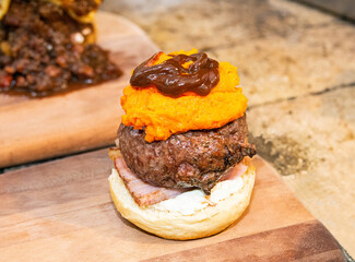 Hamburger with bread, salad, meat, cheddar cheese and sausage being prepared. Delicious burger prepared on a restaurant kitchen. Professional chef preparing burger. Burger making.
