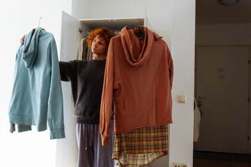 Teenager girl looking at clothes in wardrobe