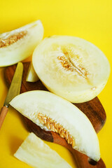 Sliced ​​ripe yellow melon on a wooden board on a yellow background