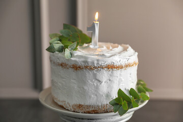 Tasty Birthday cake with burning candle and eucalyptus branches on grey table, closeup