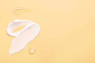 Samples of face cream on pale yellow background, top view. Space for text