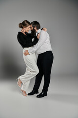 A loving couple in elegant attire poses for a portrait in a studio setting.