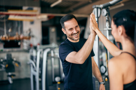 Gym partners give a high-five to each other after a great workout at the gym.