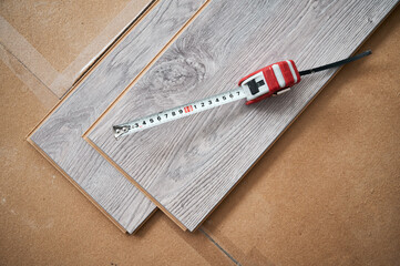 Top view of measuring tape on wooden flooring planks for home renovation and construction works....