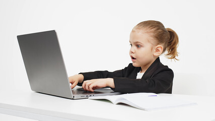 Business, little child working at a laptop on a light isolated studio background. Concept of deal, business and modern technology.