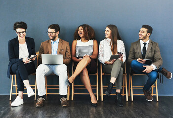 Talking, technology and business people in waiting room for interview, meeting or recruitment on chair. Hiring, HR and diversity candidates in office for opportunity, onboarding or employment