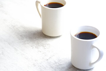 淹れたてのコーヒーが入ったふたつのマグカップで、二人が打ち合わせをしているイメージ