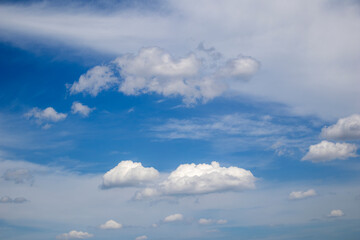 White cumulus clouds form against a vibrant blue sky