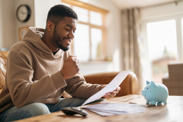 Man Reviewing Financial Documents With Piggy Bank on Table