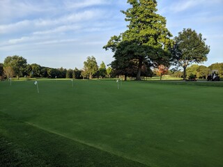 Fototapeta premium Putting hole practice on a green Golf Course with a golf cart in the background