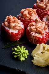 Sushi roll in tobiko caviar with salmon on a black board