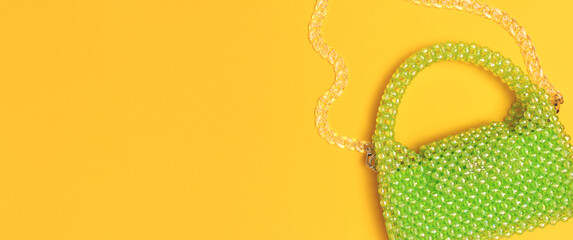 Banner with beaded handbag with chain on a yellow background.