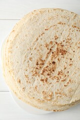 Stack of tasty homemade tortillas on white wooden table, top view